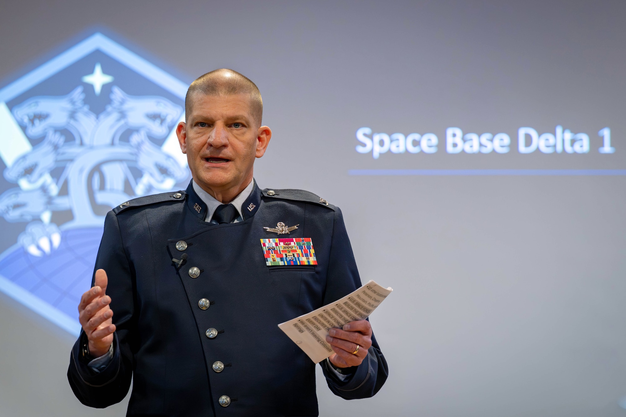 Col. Klock is standing in front of the projector screen as he addresses the audience.