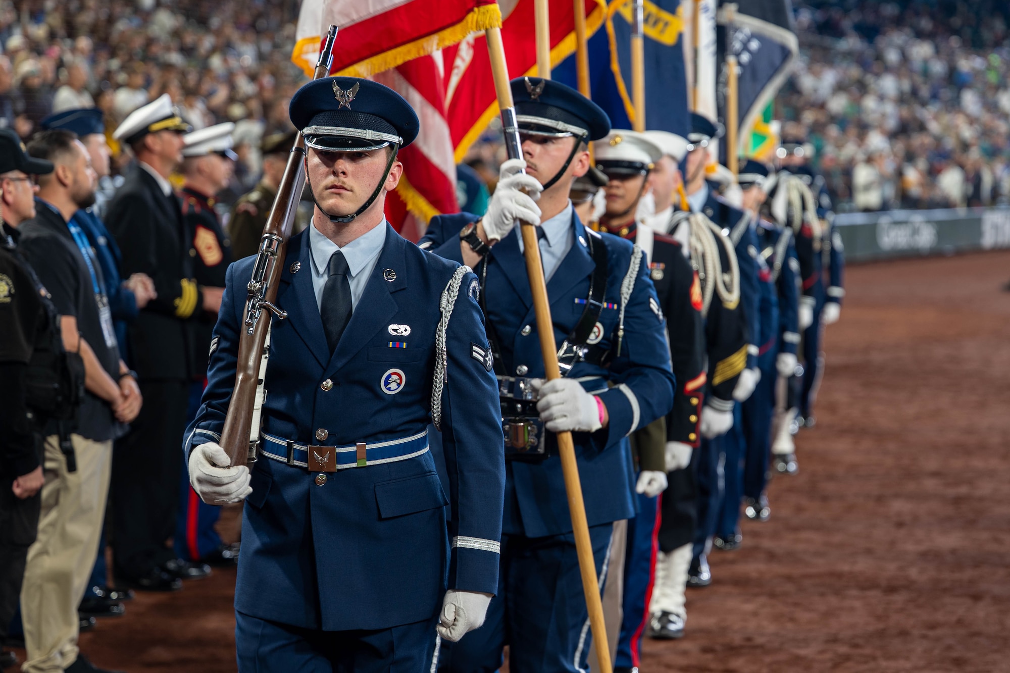 A man carrying a rifle leads a procession of flags.