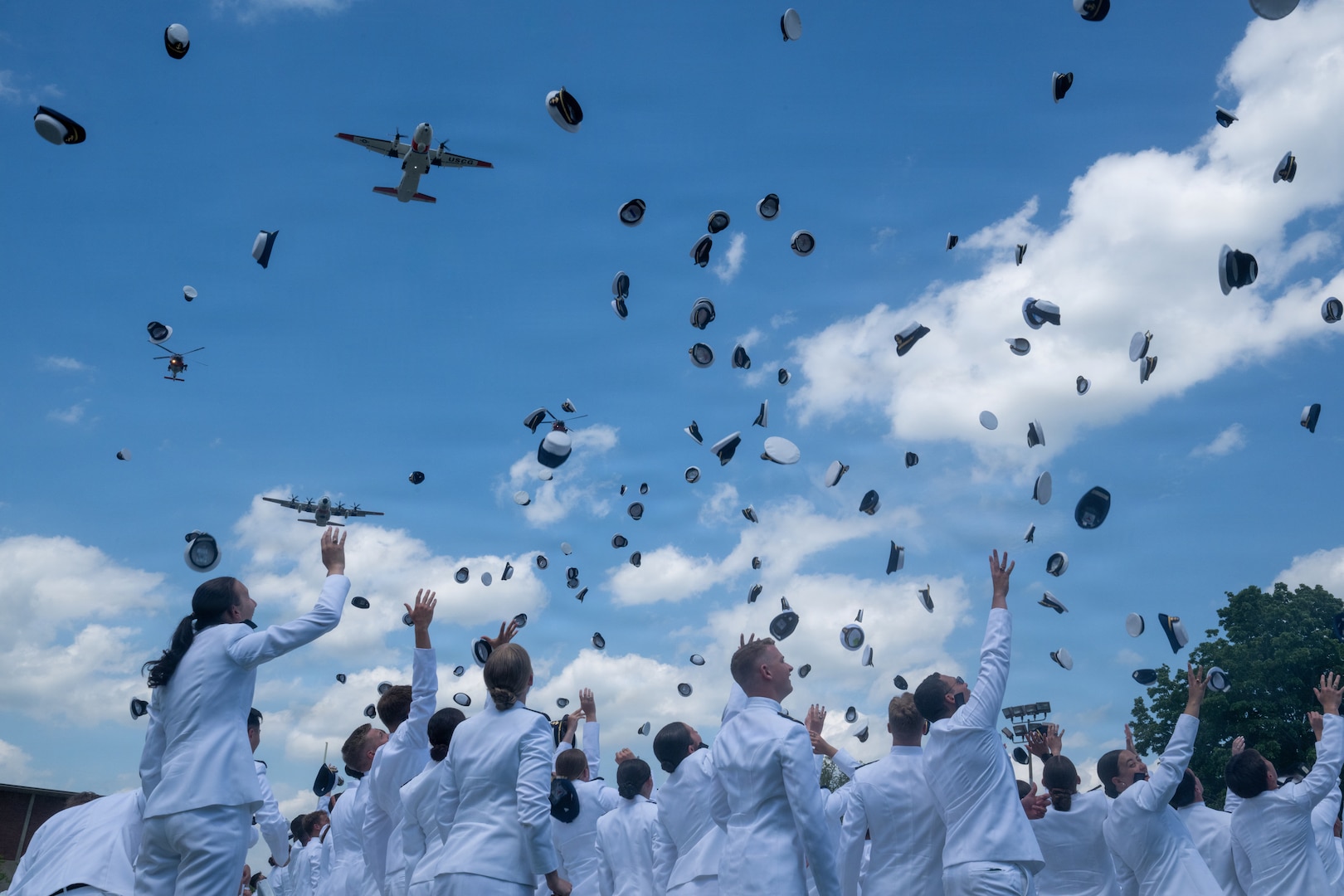 The Coast Guard Academy Class of 2026 throws their cadet combination covers into the air during a flyover at the 145th Commencement Exercise at the Coast Guard Academy, New London, Connecticut, May 20, 2026. The flyover featured various Coast Guard aircraft. (U.S. Coast Guard photo by Petty Officer 3rd Class Rajesh Harrilal)