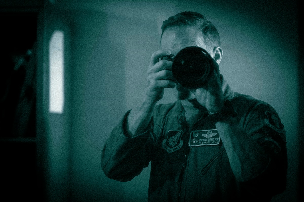 U.S. Air Force Col. Paul Davidson, 35th Fighter Wing (FW) commander, looks through the viewfinder of a camera equipped with a night vision adapter during a Wild Weasel Walk-through of the 35th FW Public Affairs unit at Misawa Air Base, Japan, May 18, 2026. (U.S. Air Force photo illustration by Senior Airman Gavin Hameed) (This image was altered to simulate white phosphorus night vision)