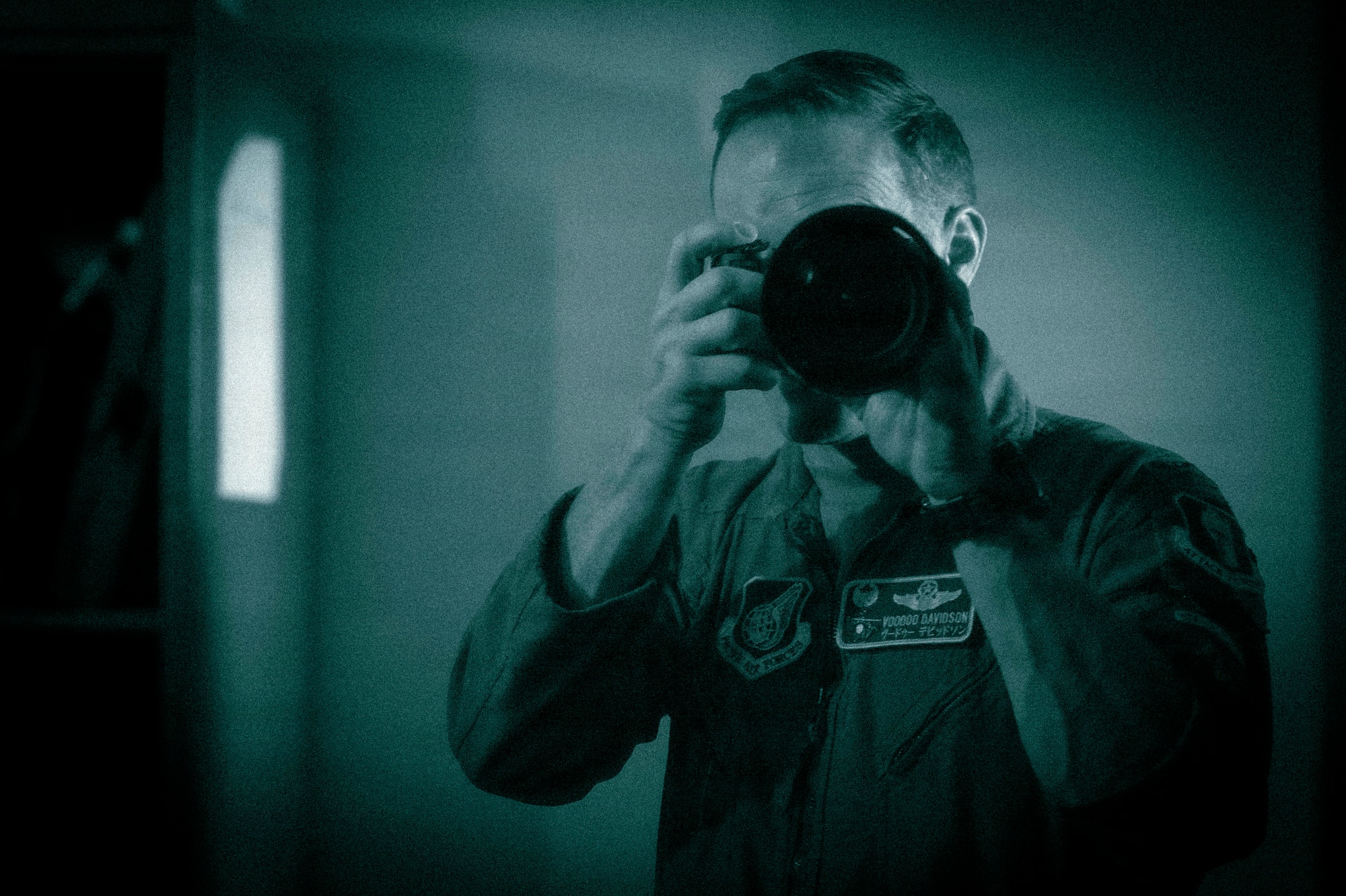 U.S. Air Force Col. Paul Davidson, 35th Fighter Wing (FW) commander, looks through the viewfinder of a camera equipped with a night vision adapter during a Wild Weasel Walk-through of the 35th FW Public Affairs unit at Misawa Air Base, Japan, May 18, 2026. (U.S. Air Force photo illustration by Senior Airman Gavin Hameed) (This image was altered to simulate white phosphorus night vision)