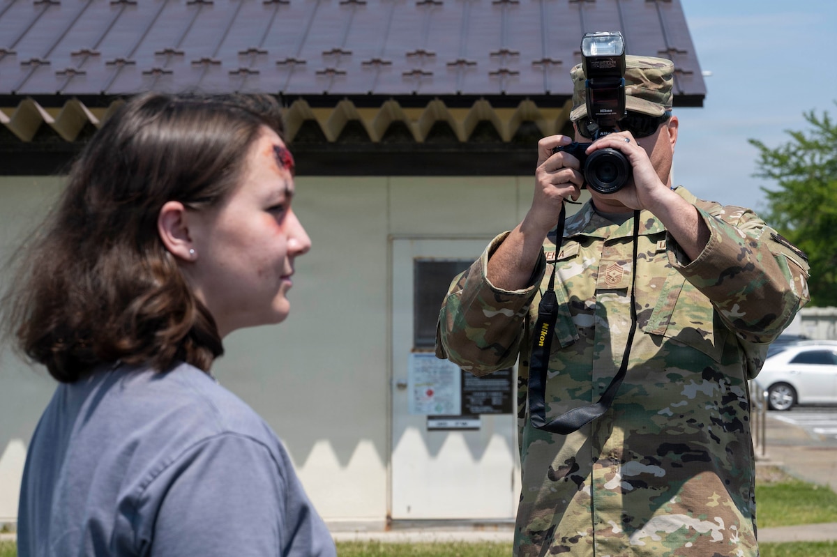 U.S. Air Force Chief Master Sgt. David Najera, 35th Fighter Wing (FW) command chief, takes a photograph of Airman 1st Class Hannah Bench, 35th FW Public Affairs specialist during a Wild Weasel Walk-through of the 35th FW public affairs unit at Misawa Air Base, Japan, May 18, 2026. (U.S. Air Force photo by Senior Airman Gavin Hameed)