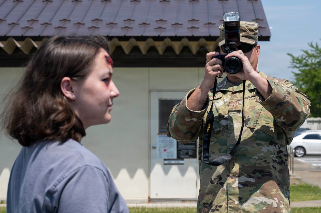 U.S. Air Force Chief Master Sgt. David Najera, 35th Fighter Wing (FW) command chief, takes a photograph of Airman 1st Class Hannah Bench, 35th FW Public Affairs specialist during a Wild Weasel Walk-through of the 35th FW public affairs unit at Misawa Air Base, Japan, May 18, 2026. (U.S. Air Force photo by Senior Airman Gavin Hameed)