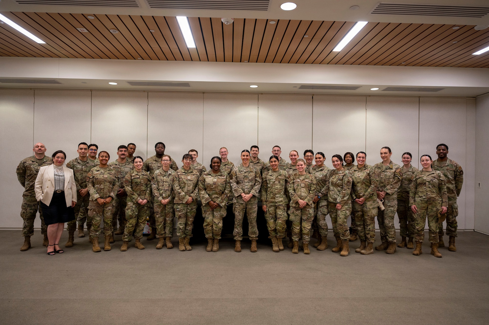 A group of military members wearing OCP camouflage uniforms stand together in two rows for a group photo.
