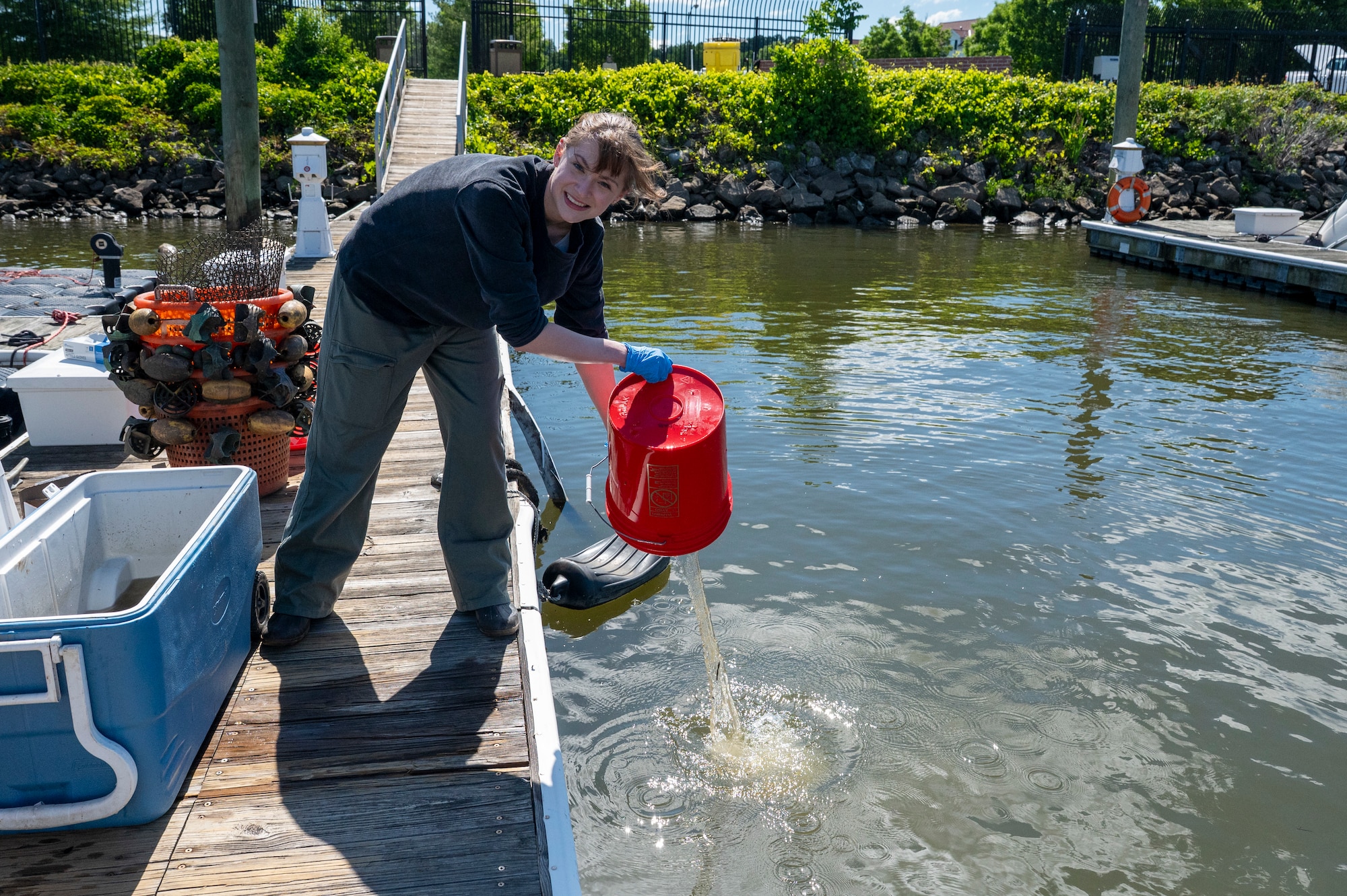 Amberleigh Ray, 11th Civil Engineer Squadron, environmental team member, pours out water from the mussel tank in preparation for a freshwater mussel deployment event at Joint Base Anacostia-Bolling, Washington, D.C., May 15, 2026. The deployment process for the mussel nursery began with draining water from the cooler containing the mussels, followed by counting, measuring, organizing and releasing the mussels into the Potomac River. (U.S. Air Force photo by Senior Airman Shanel Toussaint)