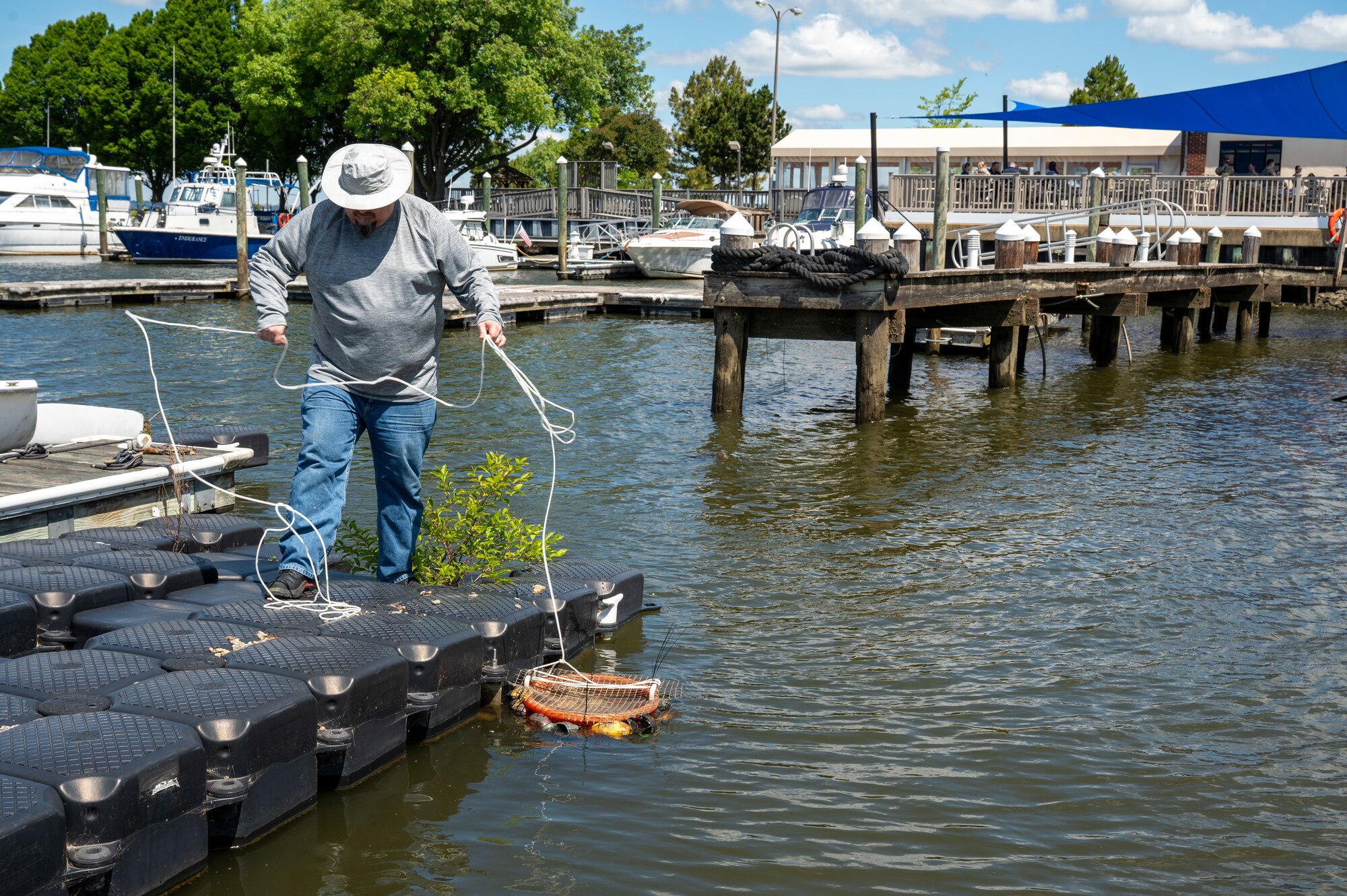 Ryan Soens, 11th Civil Engineer Squadron environmental element chief, ties buckets of mussels to the docks of the marina during a freshwater mussel deployment event at Joint Base Anacostia-Bolling, Washington, D.C., May 15, 2026. The mussel nursery program is a fundamental component of the 11th CES strategy to restore the Potomac River watershed, and represents a multi-year commitment to environmental excellence within the National Capital Region. (U.S. Air Force photo by Senior Airman Shanel Toussaint)