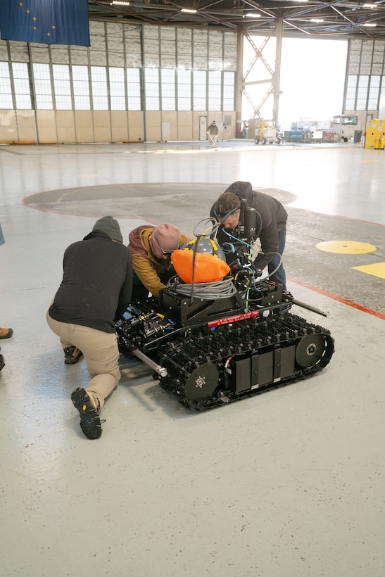 three operators inspect an AUGV system