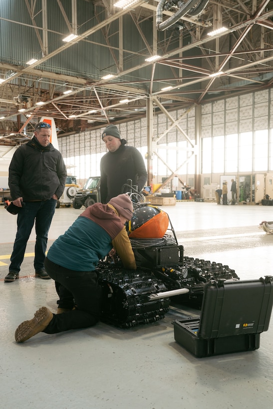 three operators inspect an AUGV system