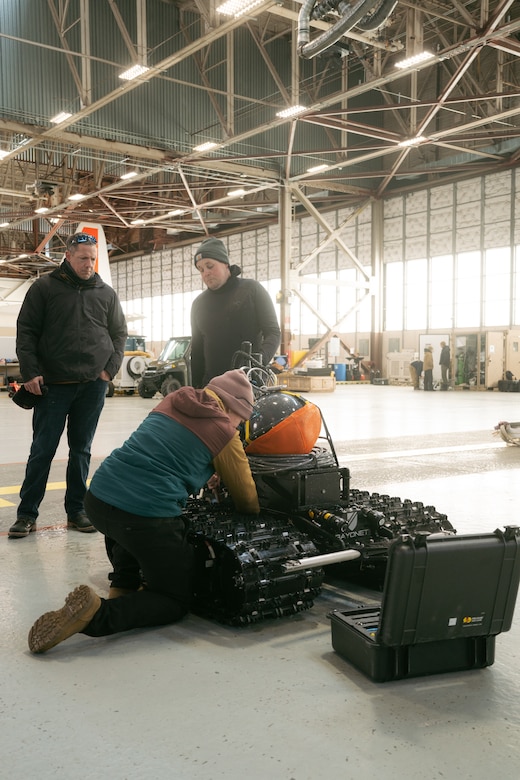 three operators inspect an AUGV system