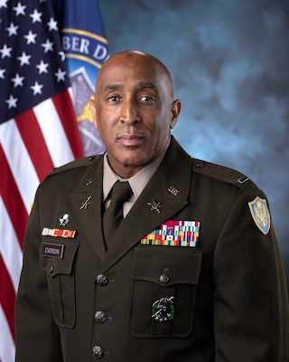 man in Army uniform standing in front of flags