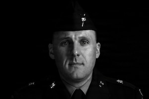 A man wearing a military dress uniform poses for a black and white photo.