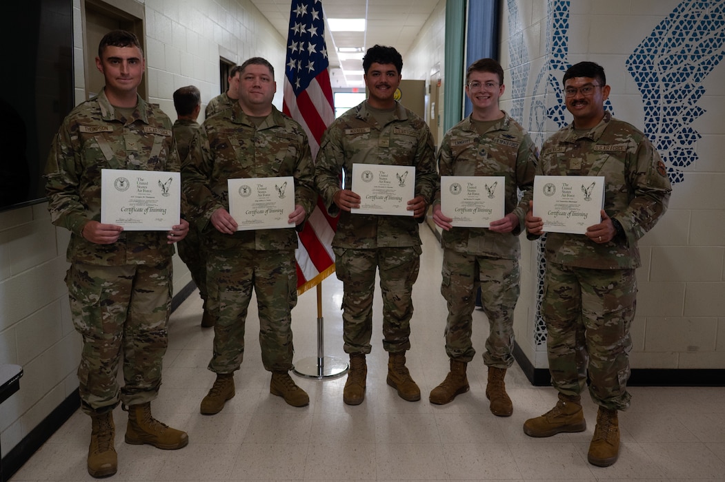 9S100D Applied Data Analysis Class 26003 poses for a group photo with their graduation certificates inside the Louis F. Garland Department of War Fire Academy at Goodfellow Air Force Base, Texas, March 25, 2026. The Special Instruments Training schoolhouse now trains Airmen and Guardians in 9S100D courses to provide the Air and Space Force with capable service members that are able to clean, transform and present data for the joint intelligence, surveillance and reconnaissance community. (U.S. Air Force photo by Senior Airman Brian Lummus)