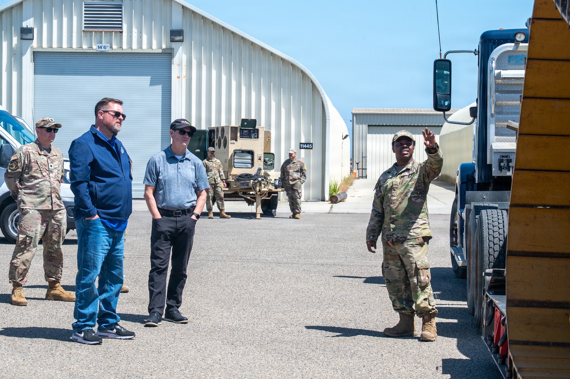 People stand outside in front of a truck while someone points and talks.