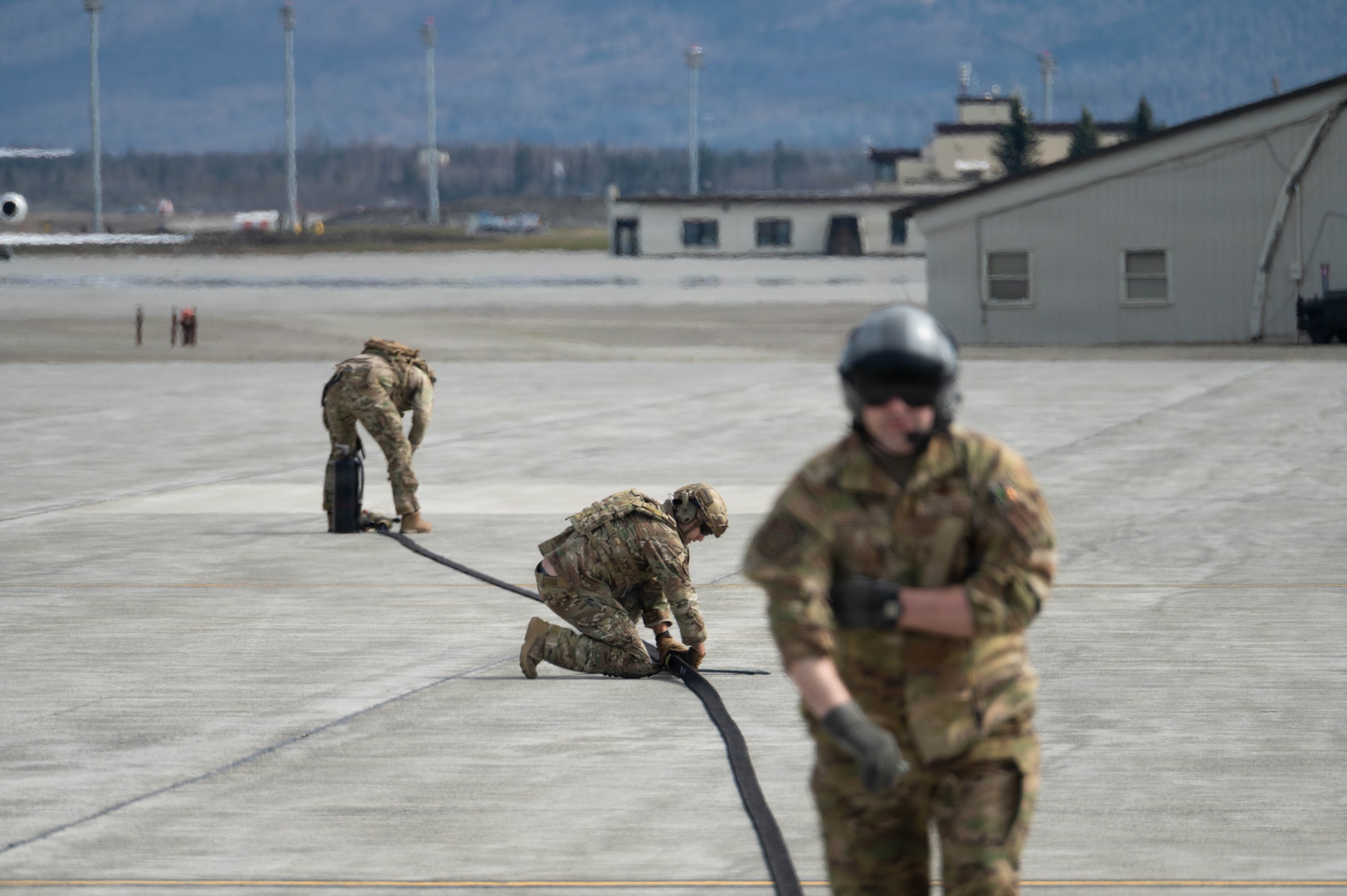 U.S. Air Force Tech. Sgt. Devan Andersen, left, 176th Logistics Readiness Squadron noncommissioned officer in charge of fuels distribution, Master Sgt. Tyler Vasquez, center, 176th Logistics Readiness Squadron fuels management specialist, and Master Sgt. Michael Gesford, 211th Rescue Squadron mobility loadmaster, complete a hose drag for a forward arming and refueling point operation at Joint Base Elmendorf-Richardson, Alaska, May 15, 2026