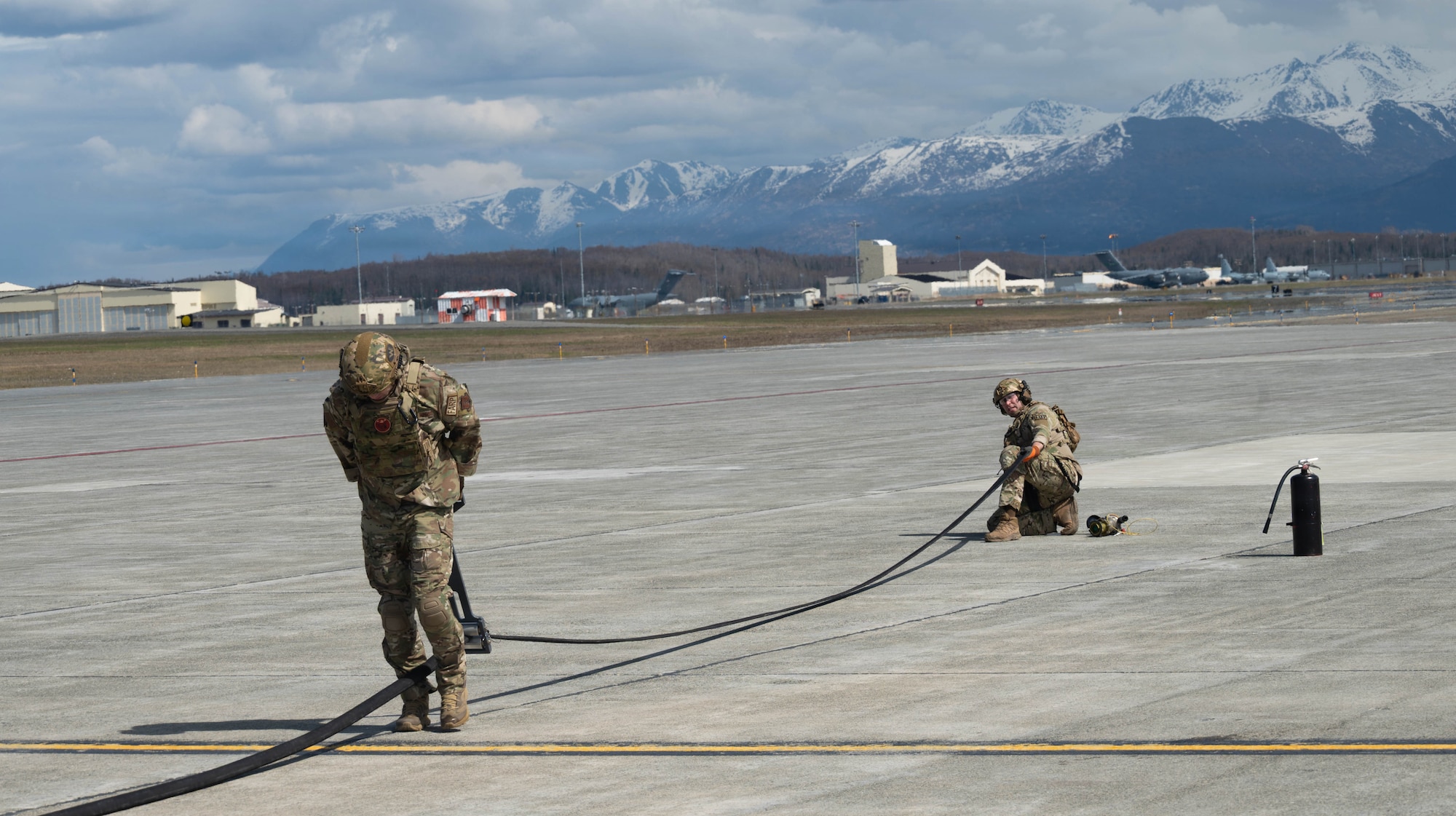U.S. Air Force Master Sgt. Tyler Vasquez, left, 176th Logistics Readiness Squadron fuels management specialist, and U.S. Air Force Tech. Sgt. Devan Andersen, 176th LRS noncommissioned officer in charge of fuels distribution, retract a fuel hose prior to a forward arming and refueling point operation at Joint Base Elmendorf-Richardson, Alaska, May 15, 2026