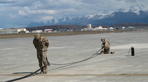 U.S. Air Force Master Sgt. Tyler Vasquez, left, 176th Logistics Readiness Squadron fuels management specialist, and U.S. Air Force Tech. Sgt. Devan Andersen, 176th LRS noncommissioned officer in charge of fuels distribution, retract a fuel hose prior to a forward arming and refueling point operation at Joint Base Elmendorf-Richardson, Alaska, May 15, 2026