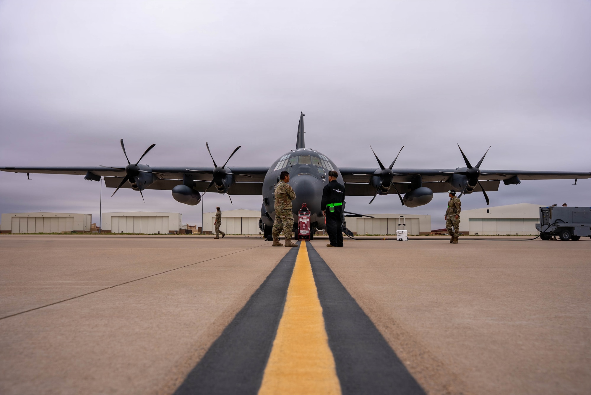 An aircraft sits on a flightline with a line on the concrete leading up to the nose on the apron