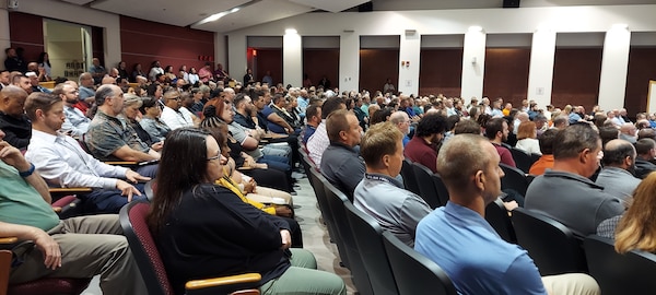 A group of people sit in chairs in an auditorium.