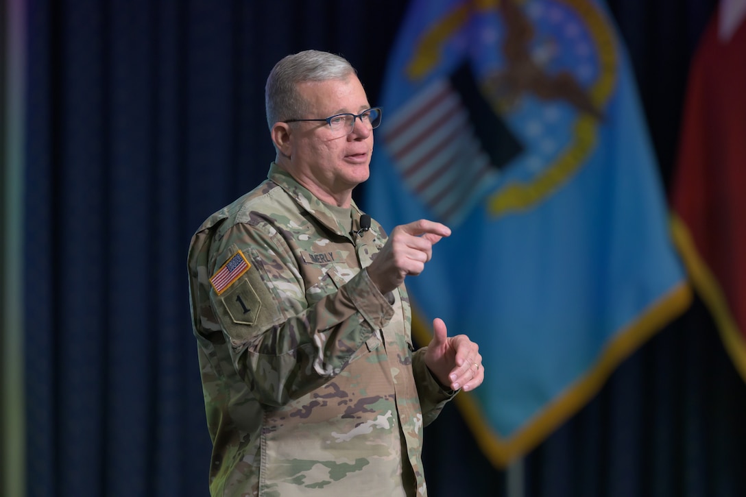 An Army lieutenant general wears a uniform and stands on a stage.