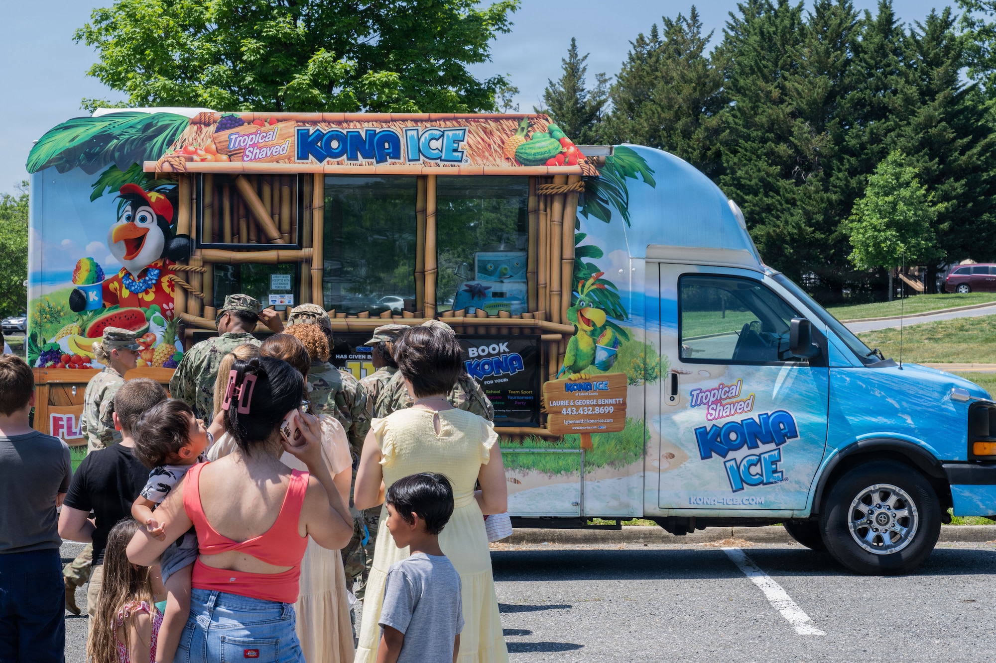 People standing on a line in front of a food truck.