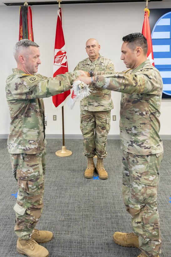 3 men in uniform fold the Expeditionary District flag