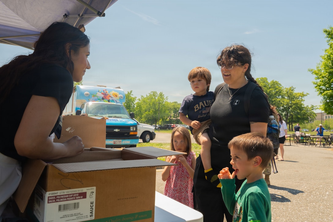 Woman with children stand in front of a table booth.