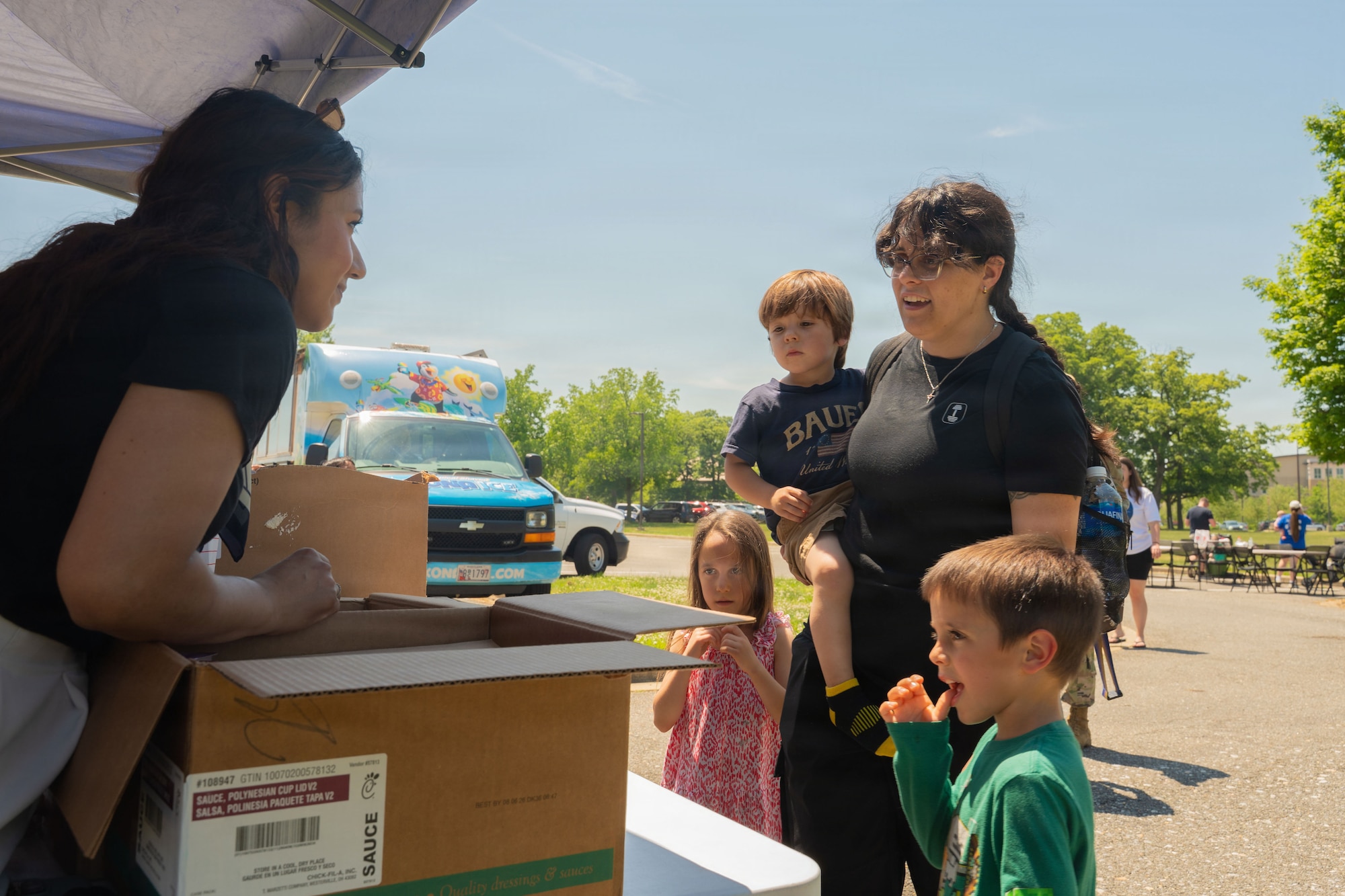 Woman with children stand in front of a table booth.