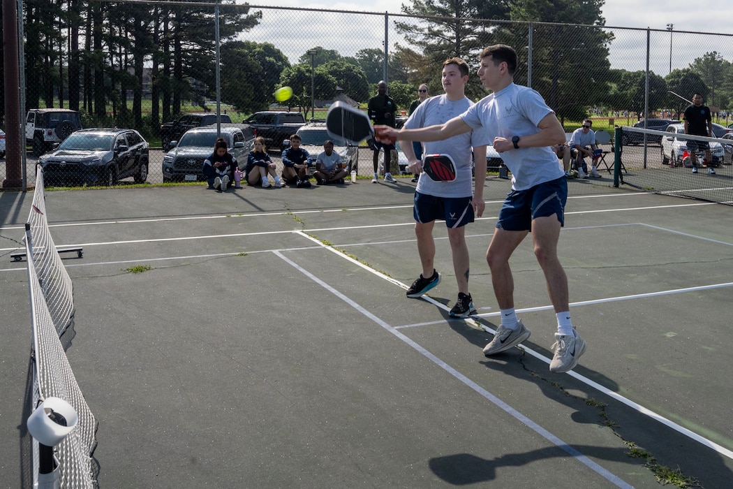 Two Airmen play pickleball in Air Force PT gear.