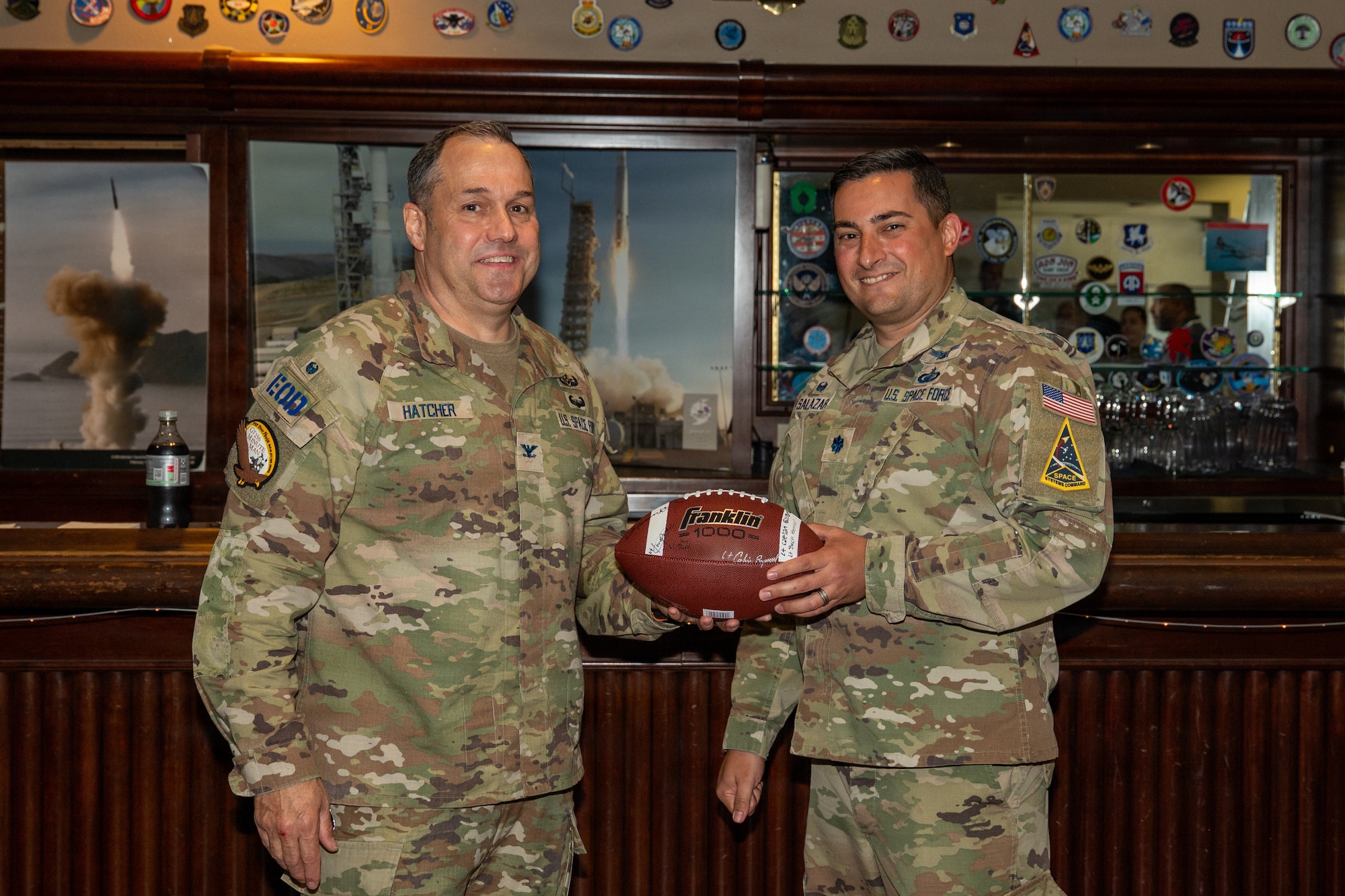 Two people stand and smile as they hold a football.