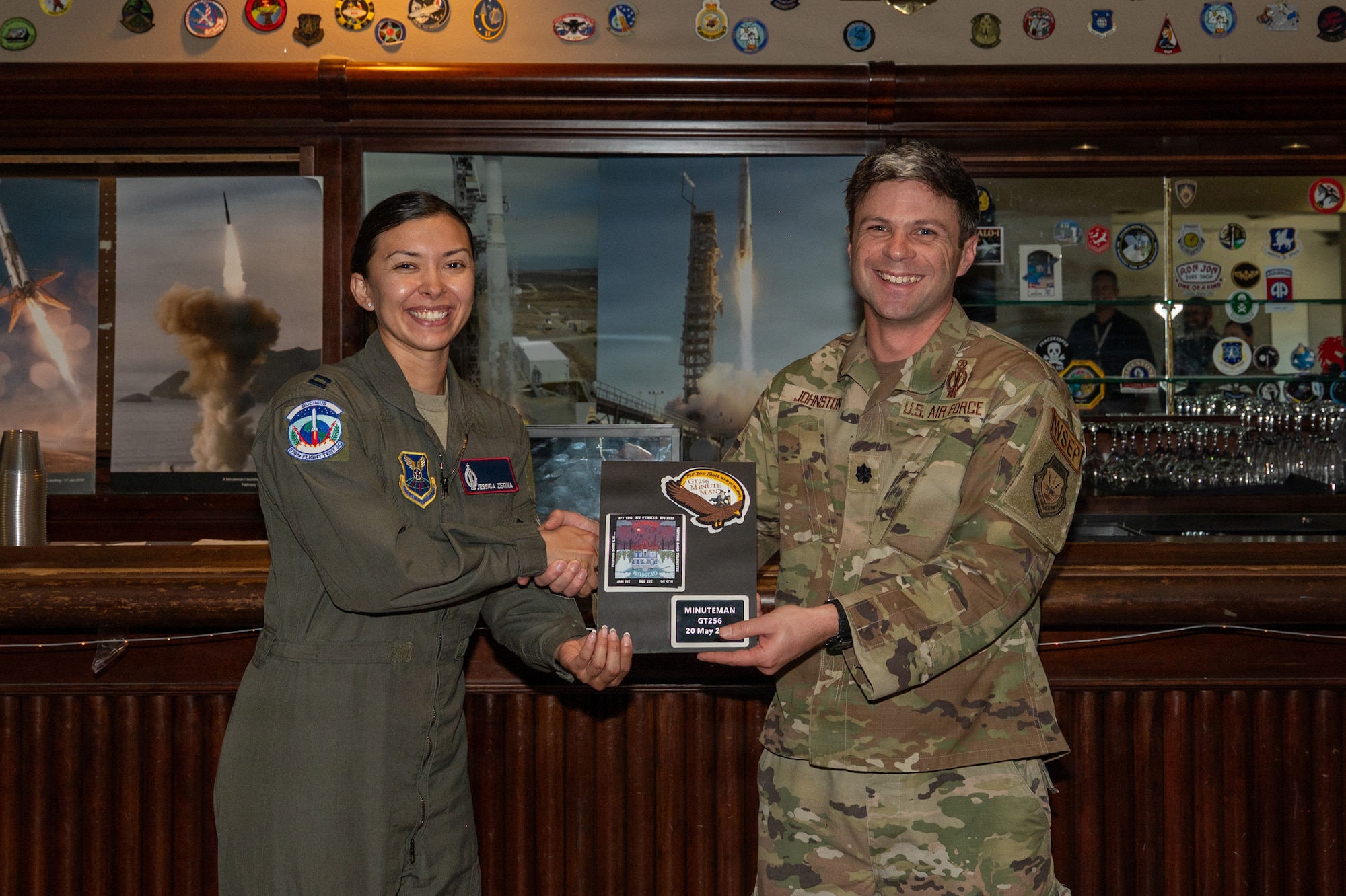 Two people hold a patch frame and smile.
