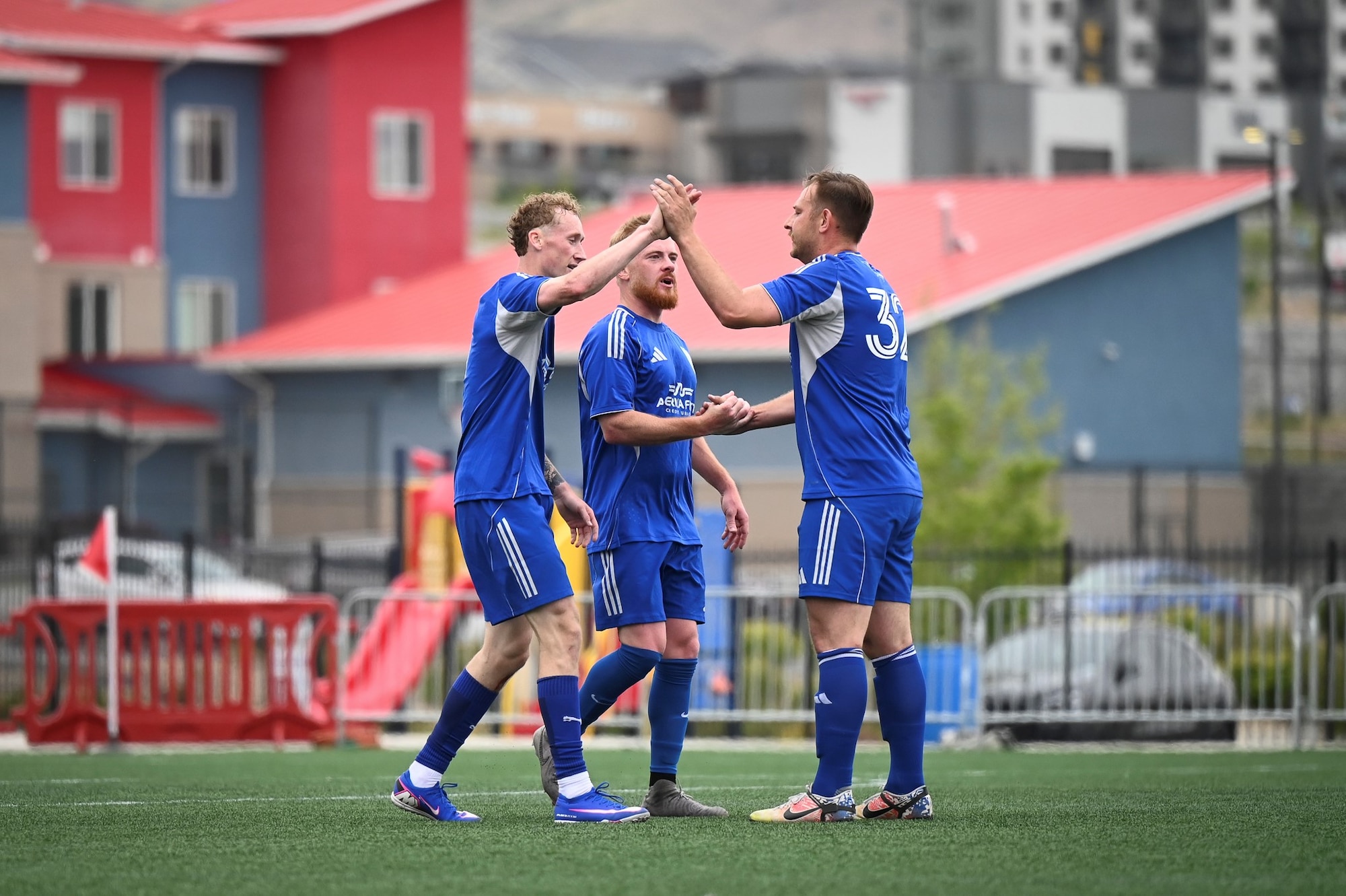 Three members of the soccer team celebrate after scoring a goal during a Commanders Cup match at Zions Bank Training Center.