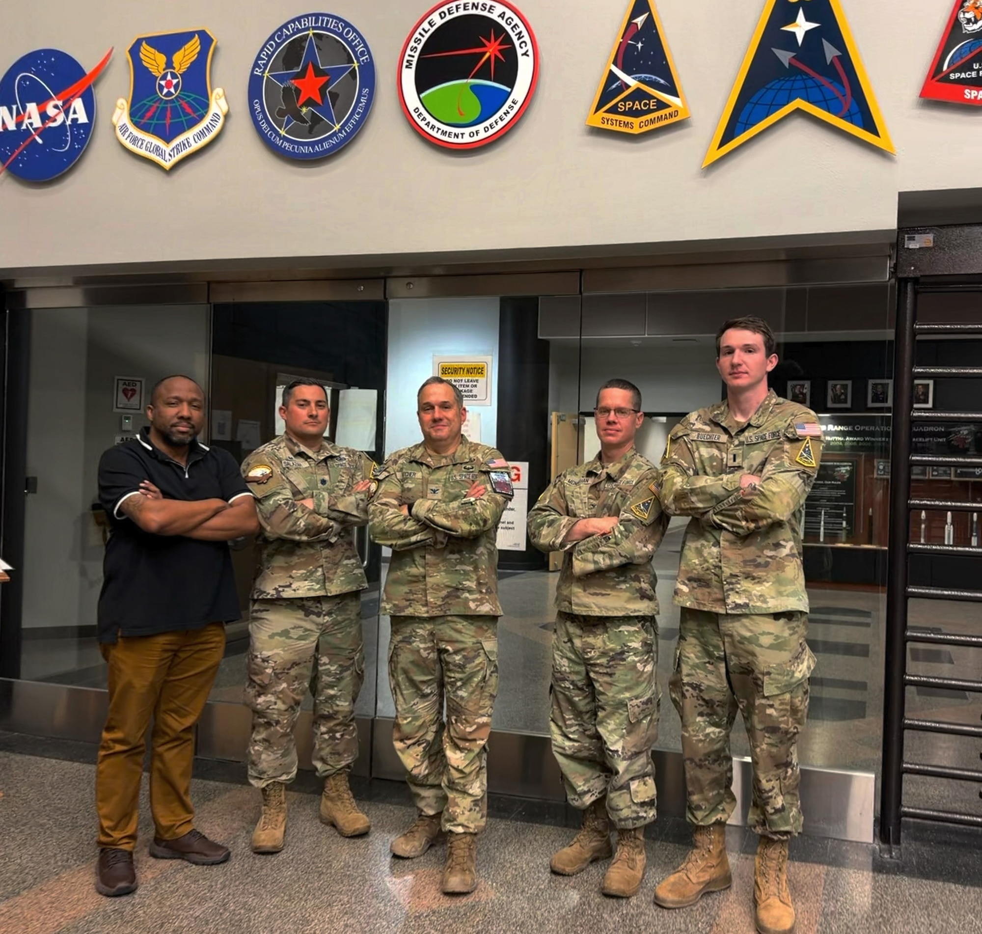 Four U.S. Space Force service members and one civilian pose at the Western Range Operation Control Center.