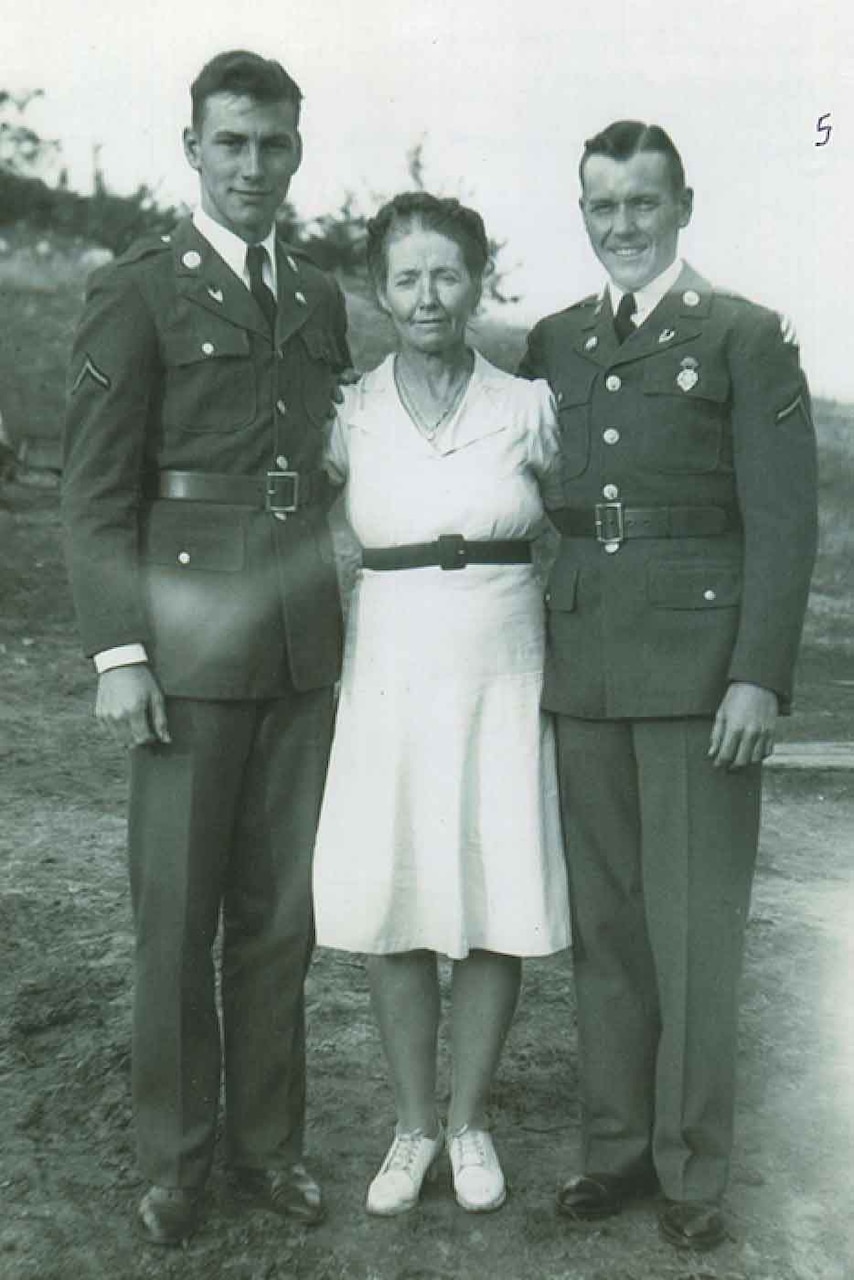 Two men wearing military uniforms and a woman pose for a photo.