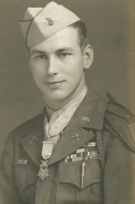 A man wearing a military uniform and a medal around his neck poses for a photo.