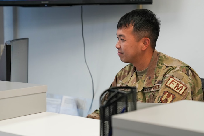 Photo shows a uniformed individual sitting behind a counter