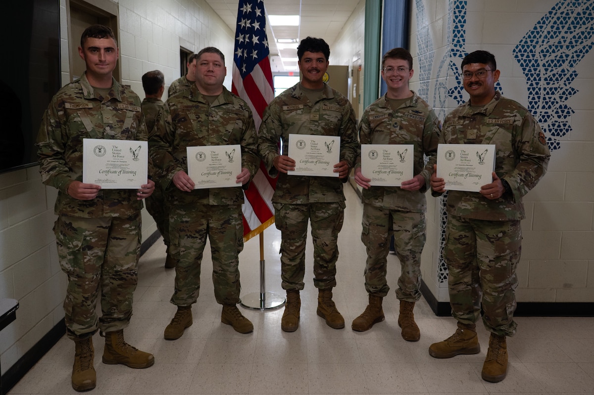 9S100D Applied Data Analysis Class 26003 poses for a group photo with their graduation certificates inside the Louis F. Garland Department of War Fire Academy at Goodfellow Air Force Base, Texas, March 25, 2026. The Special Instruments Training schoolhouse now trains Airmen and Guardians in 9S100D courses to provide the Air and Space Force with capable service members that are able to clean, transform and present data for the joint intelligence, surveillance and reconnaissance community. (U.S. Air Force photo by Senior Airman Brian Lummus)