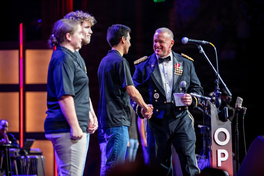 Lt. Gen. Robert Harter shakes hands with future soldier Ulysses McMahan on the Grand Ole Opry stage. Harter is on the right, and McMahan is one of six new recruits taking the oath of enlistment during the annual Salute The Troops show.