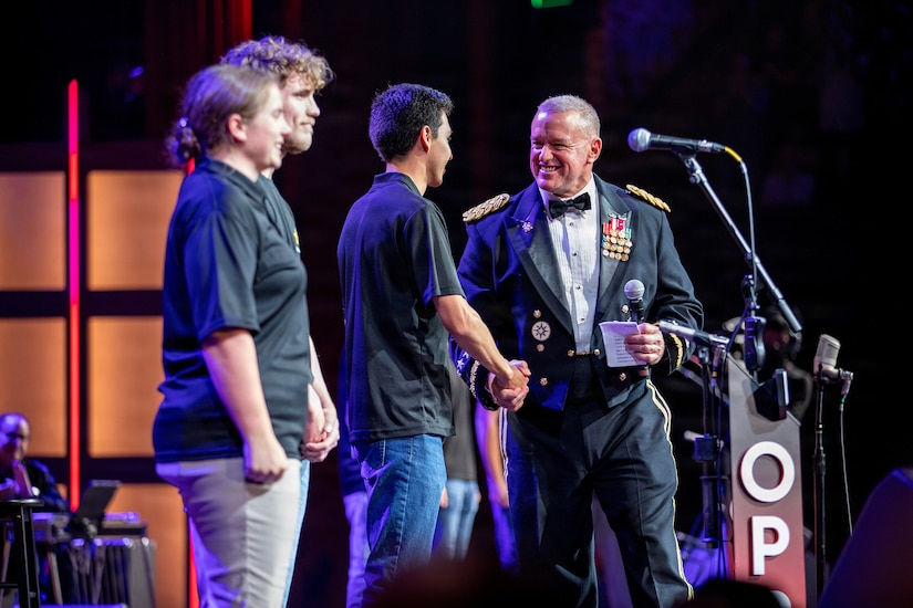 Lt. Gen. Robert Harter shakes hands with future soldier Ulysses McMahan on the Grand Ole Opry stage. Harter is on the right, and McMahan is one of six new recruits taking the oath of enlistment during the annual Salute The Troops show.