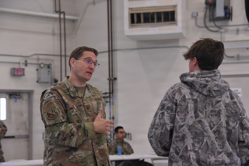 Maj. Andrew Nelson, 185th Air Refueling Wing Chaplain, stands and gestures with his hand as he speaks to a visiting student.