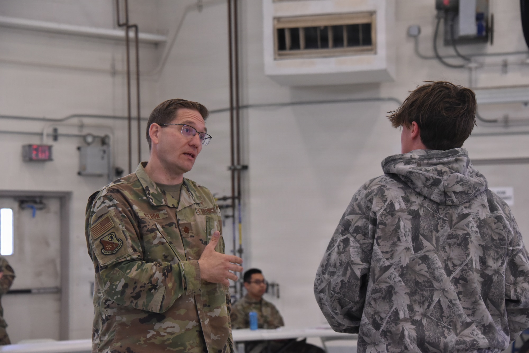 Maj. Andrew Nelson, 185th Air Refueling Wing Chaplain, stands and gestures with his hand as he speaks to a visiting student.