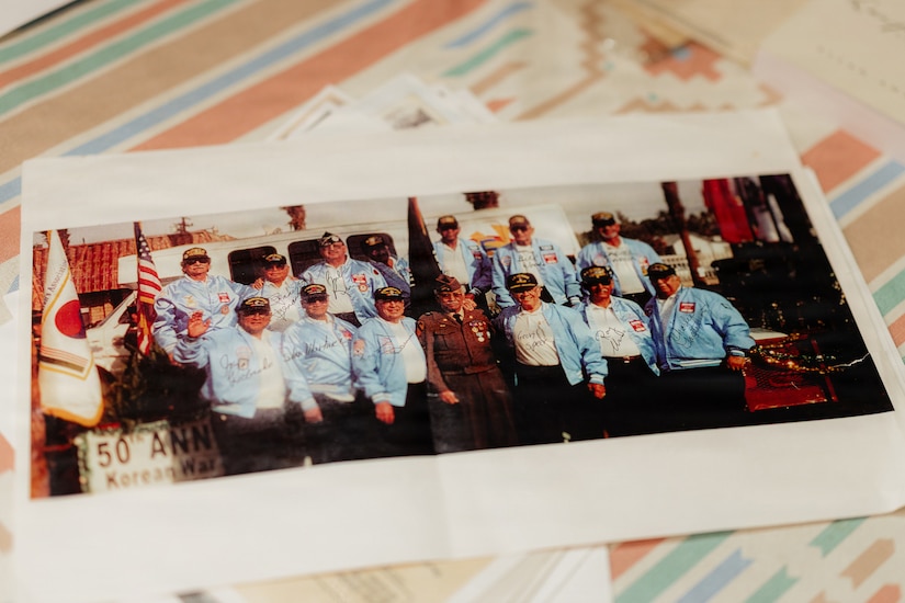 A photo of 14 men in jackets and hats posing together is displayed on a table.