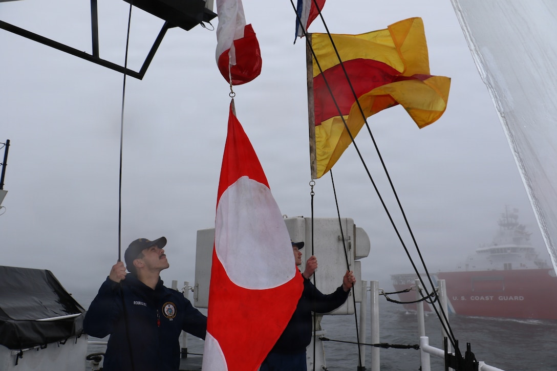 U.S. Coast Guard Petty Officer 2nd Class Jaiden Rodriguez and U.S. Coast Guard Petty Officer 3rd Class Donovan Weiss, crewmembers aboard USCGC Waesche (WMSL 751) hoist signal flags as part of a Passing Exercise and Visual Communications exercise with USCGC Storis (WAGB-21) in the Bering Sea, April 14, 2026. The primary mission of the patrol was the enforcement of fisheries laws to ensure the sustainability of our nation’s living marine resources. (U.S. Coast Guard photo by Petty Officer 3rd Class Lillian Escobar)