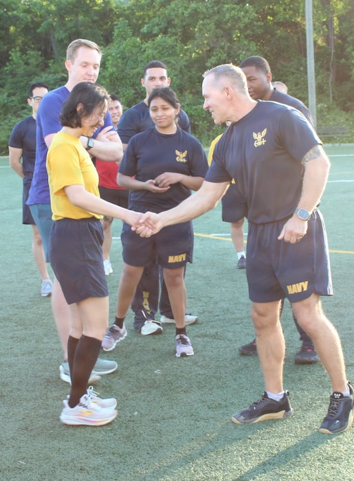The Commanding Officer of Navy Medicine Readiness and Training Command (NMRTC) Patuxent River, Capt. Ken Radford,  shakes hands with Hospital Corpsman 2nd Class Ria Tumladhamar while presenting a Memorial Day coin to the winning crew of the modified 'Murph' challenge at the Naval Air Station Patuxent River Drill Hall Field.

The command modified the grueling workout into a team event to foster camaraderie, breaking Sailors into groups to partition the repetitions. The winning team members recognized by Radford are, from left to right, Tumladhamar, Lieutenant Cole Engstrom, Hospital Corpsman 2nd Class Maria Cabrera, and Lieutenant j.g. Kashad Haston.

The monthly command physical training event was held to honor the upcoming Memorial Day weekend and pay tribute to Navy SEAL Lt. Michael Murphy, who was killed in action in Afghanistan in 2005 and posthumously awarded the Medal of Honor.