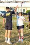 Assistant Command Fitness Leader Hospital Corpsman 3rd Class Lucas Arteaga, left, high-fives Command Fitness Leader Chief Hospital Corpsman Amanda Ellis at the Naval Air Station Patuxent River Drill Hall Field during the command’s monthly physical training event.

The two fitness leaders helped coordinate and drive motivation as Navy Medicine Readiness and Training Command (NMRTC) Patuxent River personnel took on a modified version of the 'Murph' challenge to foster unit cohesion and build camaraderie ahead of the Memorial Day weekend. Adding to the patriotic spirit of the morning, personnel wore either traditional Navy PT gear or red, white, and blue coordinated attire. 

The workout honors Navy SEAL Lt. Michael Murphy, who was killed in action in Afghanistan in 2005 and posthumously awarded the Medal of Honor. The traditional routine consists of a 1-mile run, 100 pull-ups, 200 push-ups, 300 squats, and a final 1-mile run.
