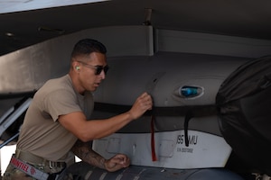 U.S. Air National Guard Staff Sgt. Jacob Montiel, a weapons technician assigned to the 195th Fighter Squadron Aircraft Maintenance Unit removes a pin from an F-16 Fighting Falcon during the 2026 Weapons Load Competition at Morris Air National Guard Base, Ariz., May 1, 2026. The annual event strengthens espirit de corps while reinforcing the wing's focus on readiness and combat capability. (U.S. Air National Guard photo by Staff Sgt. Guadalupe Beltran)