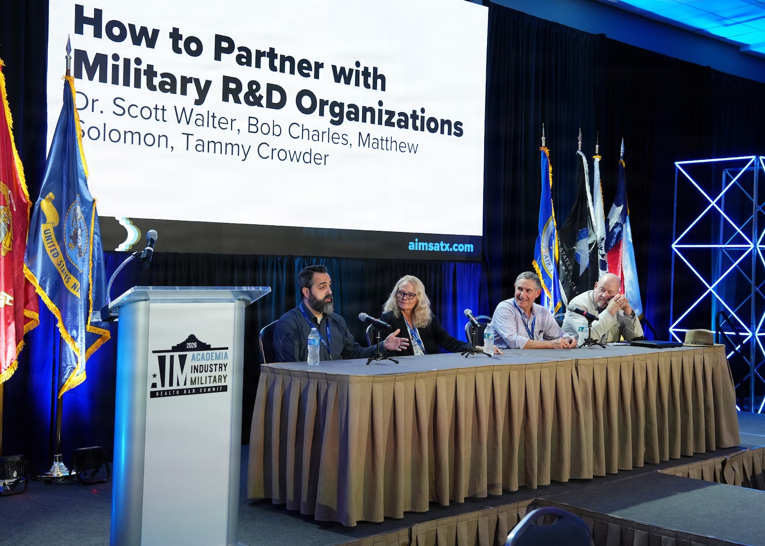 SAN ANTONIO – (May 19, 2026) – Dr. Matthew Solomon (left), science program manager, assigned to Naval Medical Research Unit (NAMRU) San Antonio, participated in “How to Partner with Military Research & Development Organizations” panel during the annual AIM Health R&D Summit held at the Henry B. Gonzalez Convention Center. Joining Solomon were (left to right) Dr. Tammy Crowder, director, Office of Research and Technology Application, U.S. Army Institute of Surgical Research; Bob Charles, chief of Medical Research Collaboration Law, Defense Health Agency; and Dr. Scott Walter, director, Tech Transfer, U.S. Air Force 59th Medical Wing. Designed to promote cross-sector collaboration in the development of life-saving battlefield technologies, the one-day summit brings together top innovators from academia, industry, and the military to accelerate the research, development, and commercialization of transformative medical technologies. Collaborating and working alongside a wide range of research and development partners keeps Navy Medicine Research & Development (NMR&D) abreast of best practices and advances in medical knowledge. NAMRU San Antonio, part of NMR&D conducts gap-driven combat casualty care, craniofacial, and directed energy research in support of Navy, Marine Corps and joint U.S. warfighter health readiness and lethality while engaged in routine and expeditionary operations. (U.S. Navy photo by Burrell Parmer, NAMRU San Antonio Public Affairs/Released)