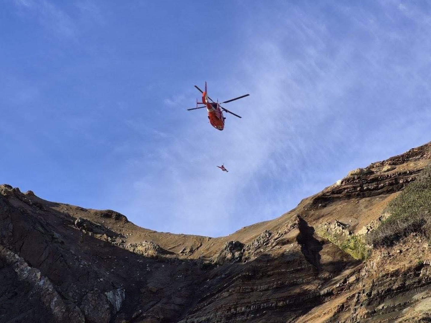 A Coast Guard MH-65 Dolphin aircrew from Coast Guard Air Facility Newport lowers Petty Officer 2nd Class Ben Sobels, Coast Guard Aviation Survival Technician onto God's Thumb in Lincoln City, Oregon, May 24, 2026.