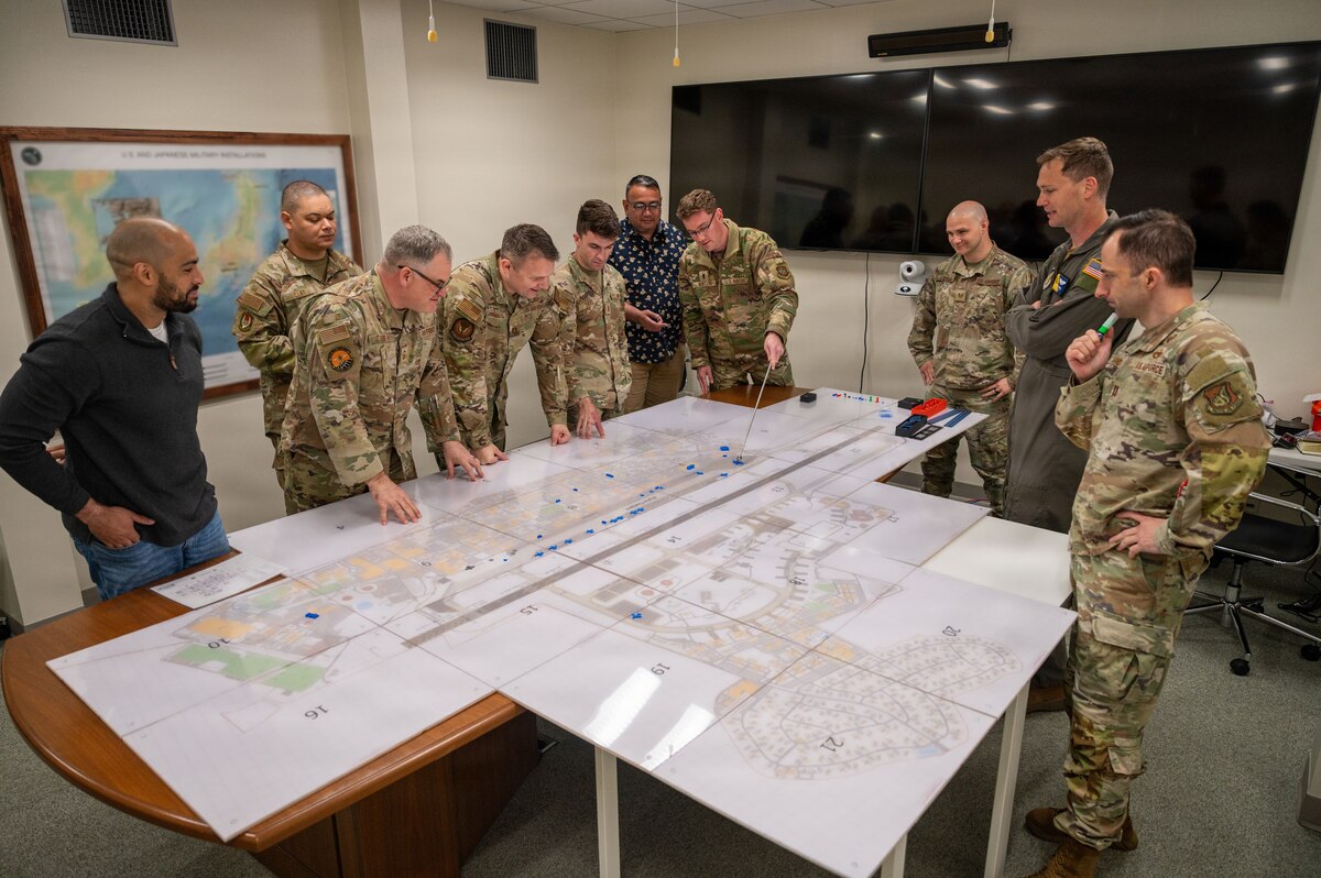 Airmen move pieces around on a map.