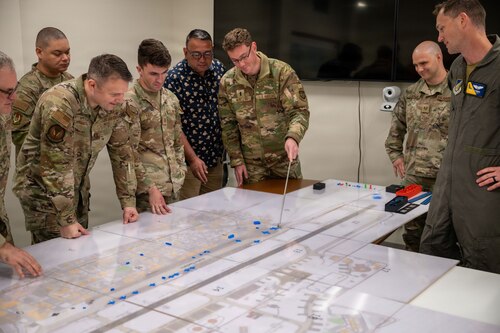 Airmen move pieces around on a map.