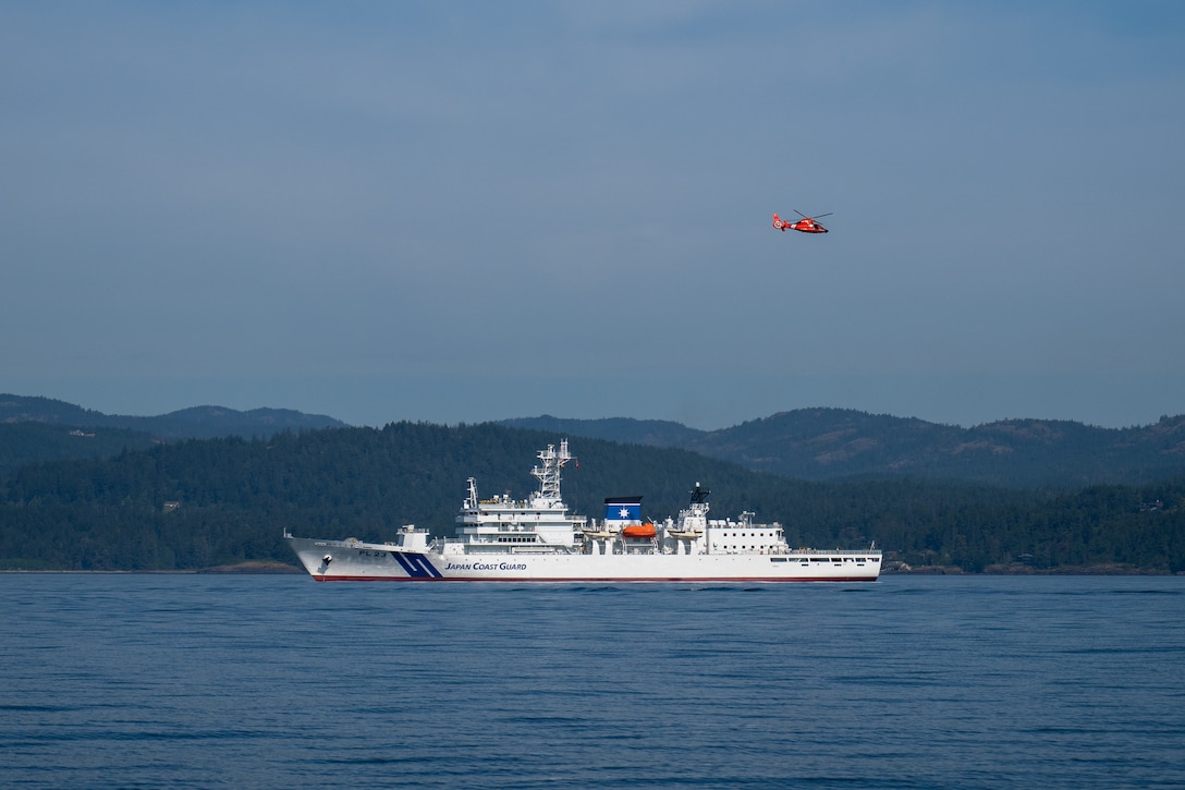 An MH-65 Dolphin helicopter from U.S. Coast Guard Air Station Port Angeles flies over Japan Coast Guard ship Itsukushima during a joint search and rescue exercise in the Strait of Juan de Fuca, May 21, 2026.